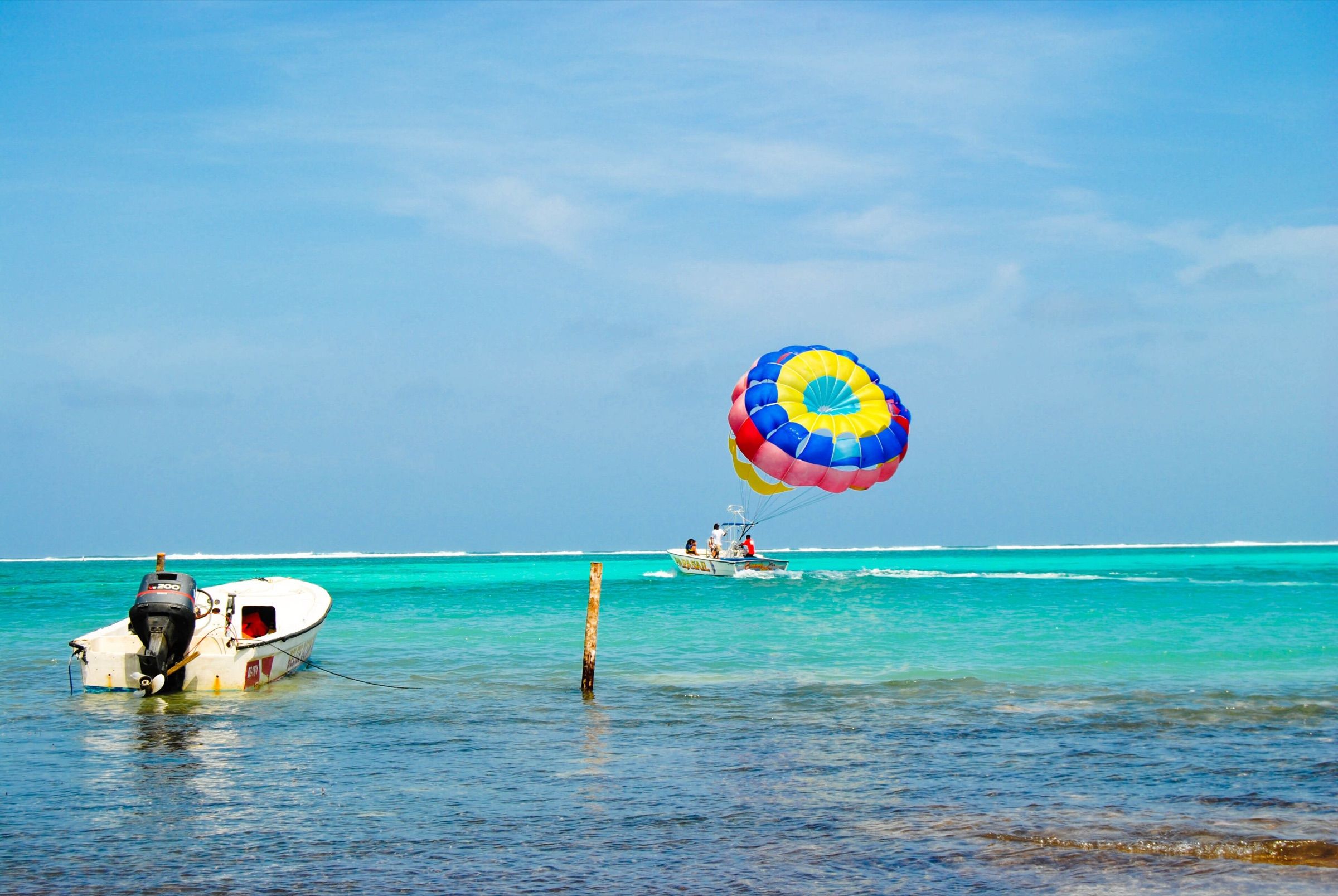 Turquoise water off Ambergris Caye with a skiff in the shallows and the Belize Barrier Reef breaking on the horizon