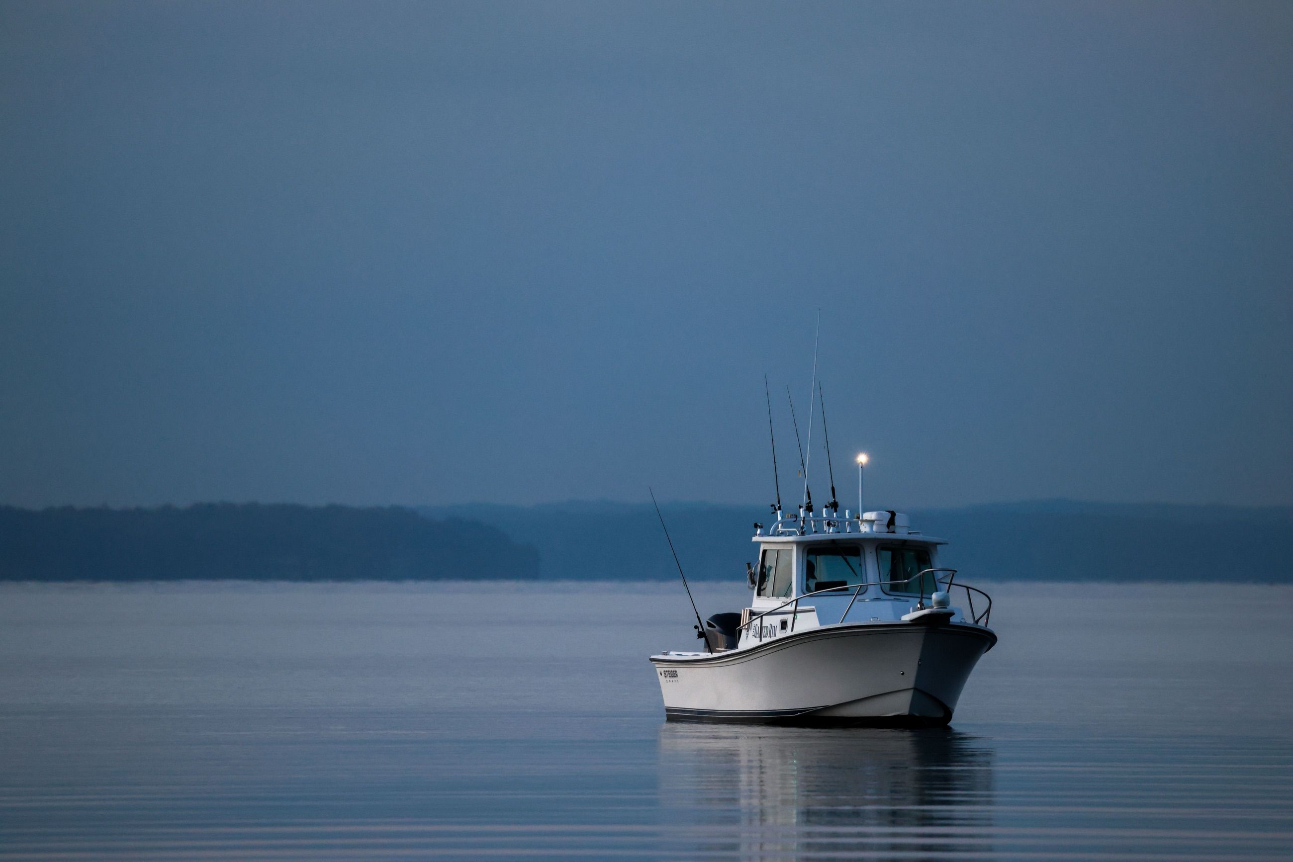 Cabin fishing boat anchored on still water at dawn