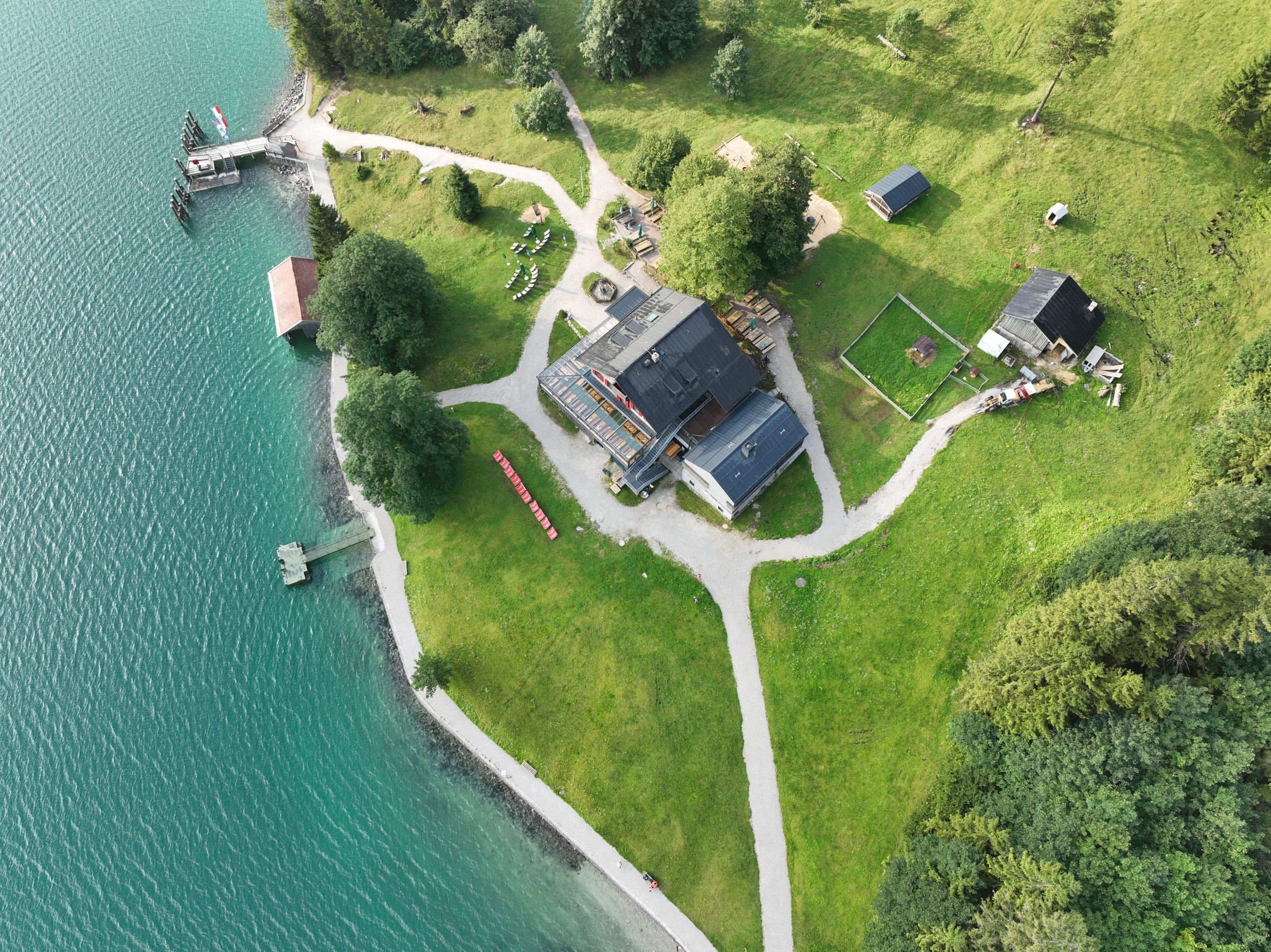 Aerial view of a waterfront lodge with a boathouse, pier and lawns beside a clear lake