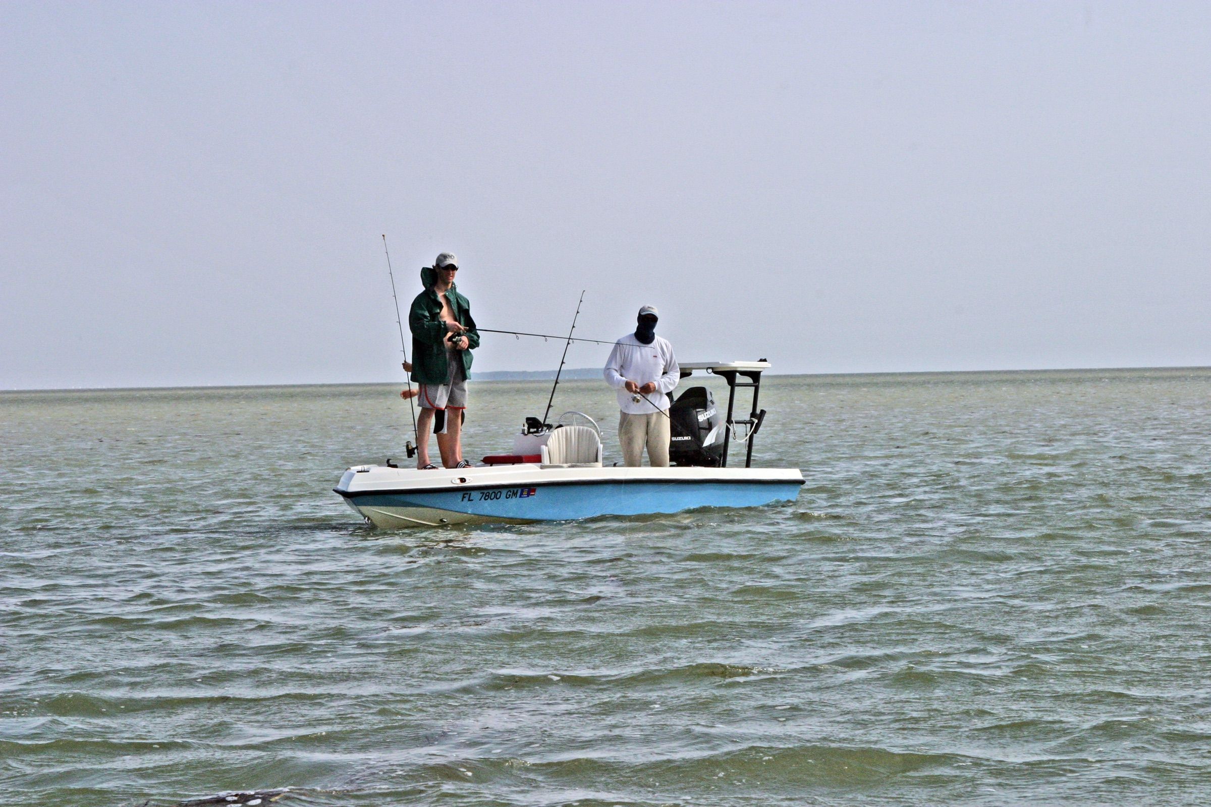 Two anglers casting from the deck of a flats boat on calm open water in Florida Bay