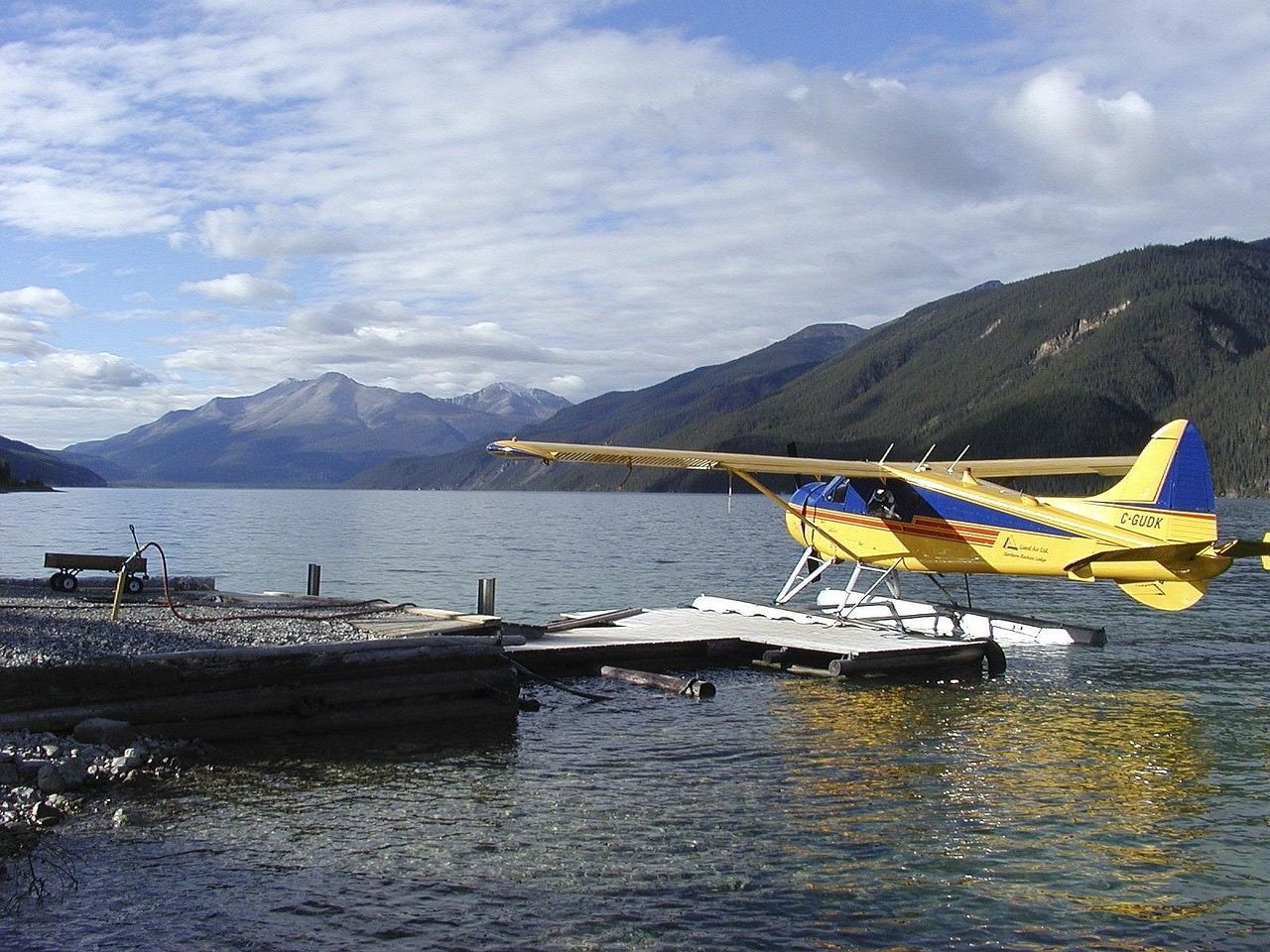 A yellow floatplane tied to a dock on a mountain lake in Yukon
