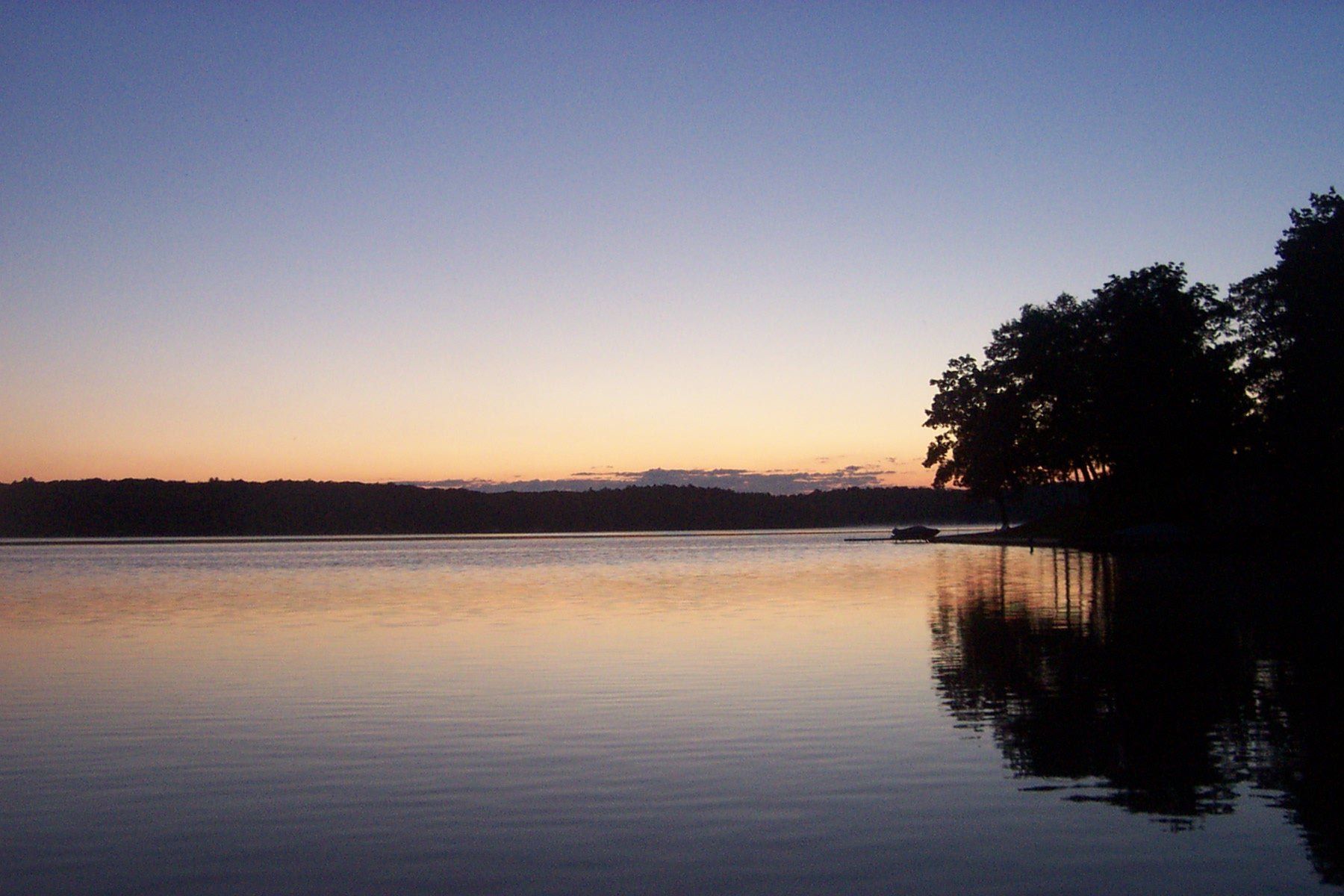 Hamlin Lake glows pale orange at dusk beside a silhouetted wooded point