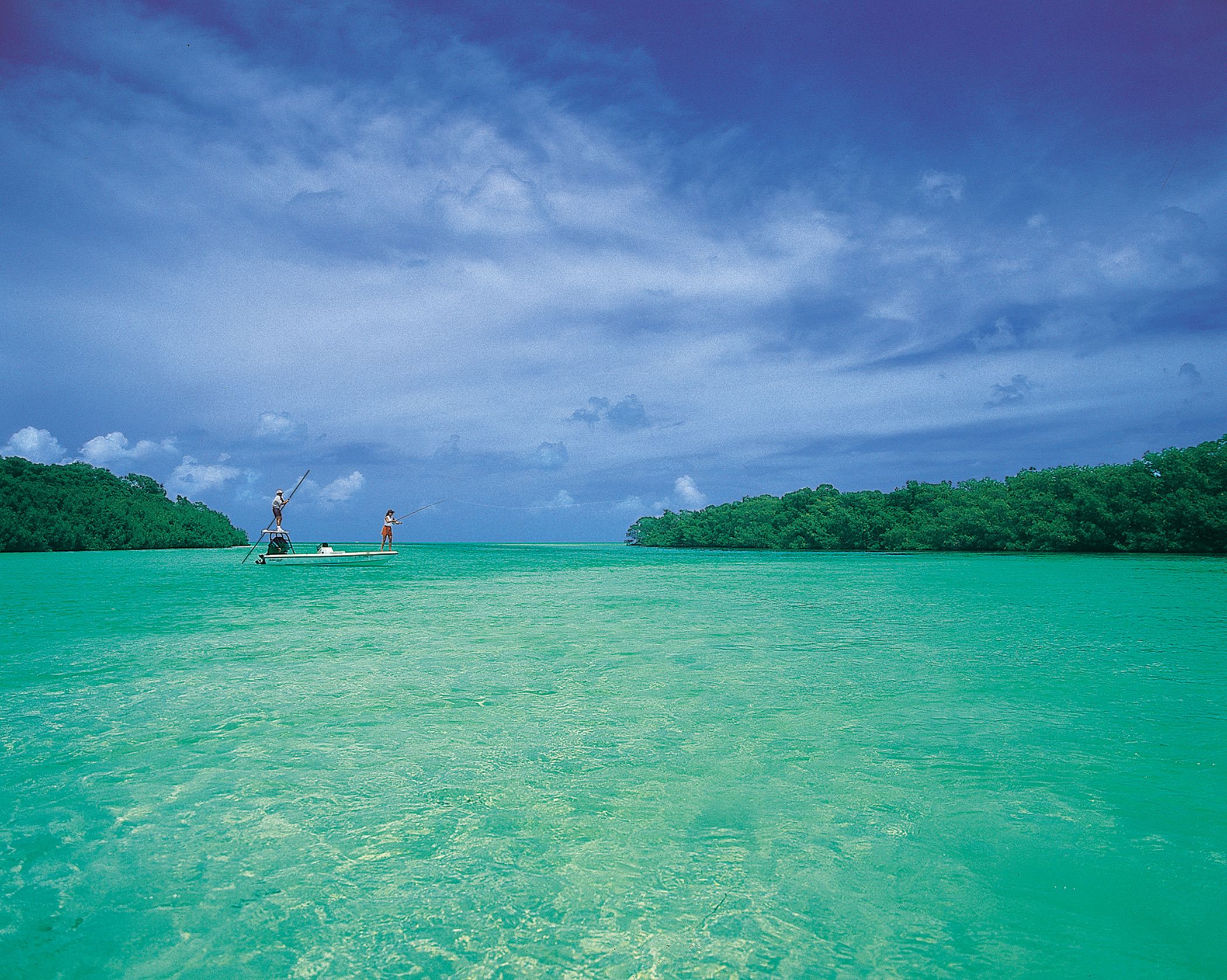 Two anglers flats fishing on clear aquamarine water between mangrove islands near Islamorada