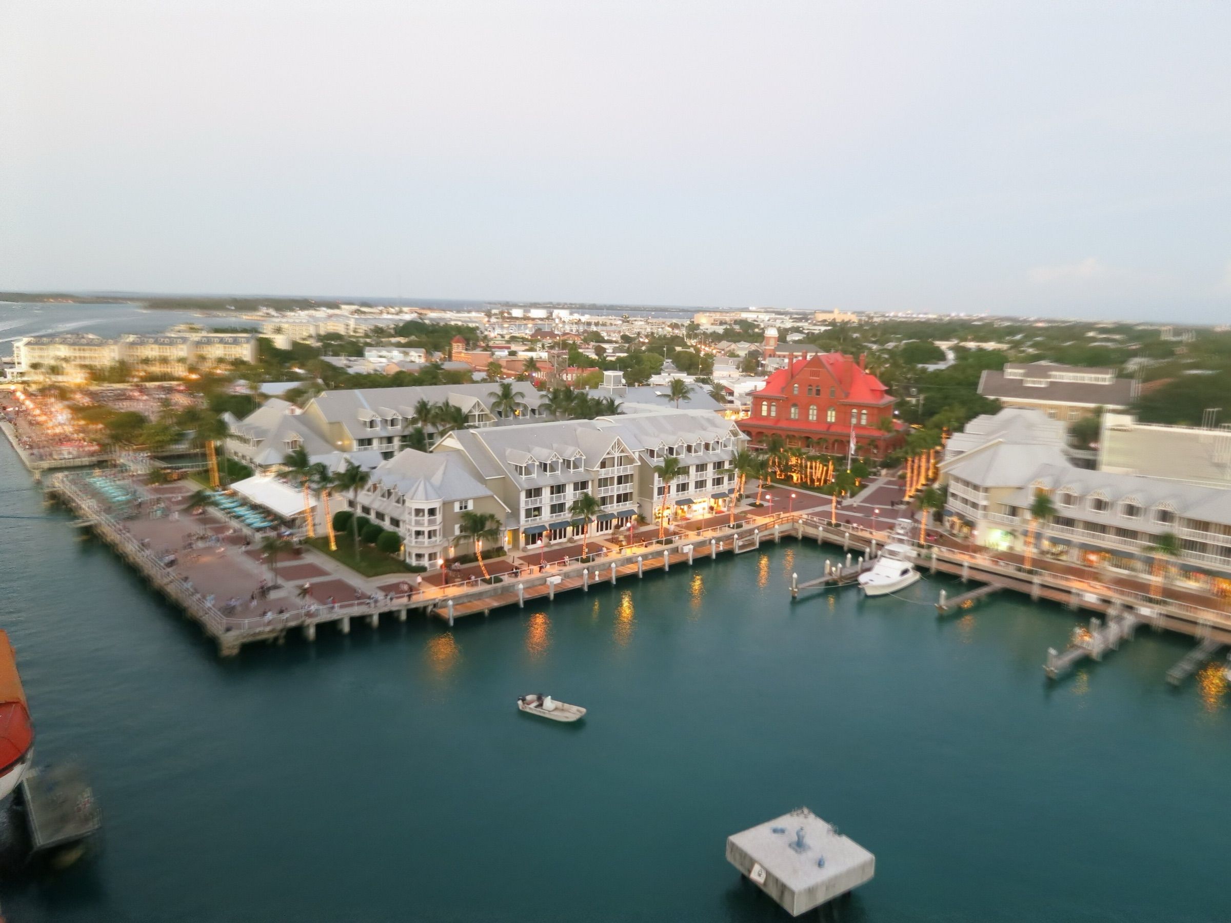 Aerial view of the Key West harbor waterfront at dusk, with docks, a small boat and the old town behind
