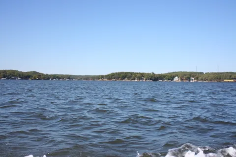 Open water on Lake of the Ozarks with lake homes and docks along a wooded shoreline