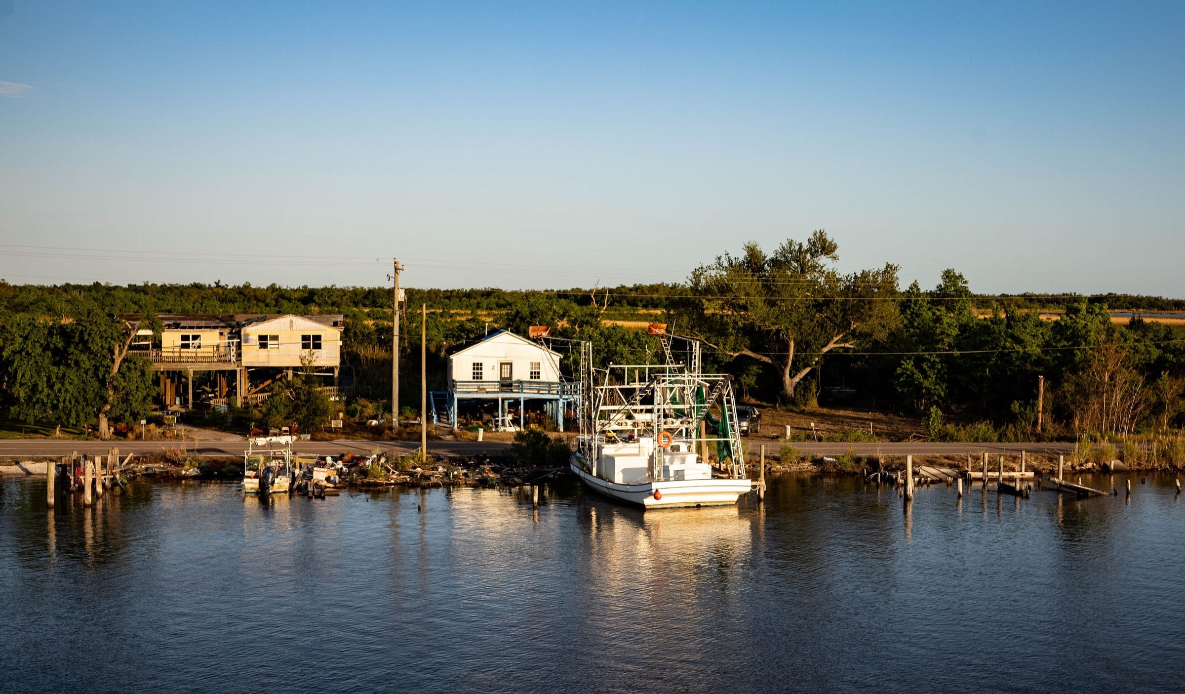 Boats and waterfront homes along a calm bayou at evening in Dulac