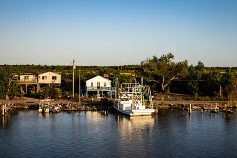 Boats and waterfront homes along a calm bayou at evening in Dulac