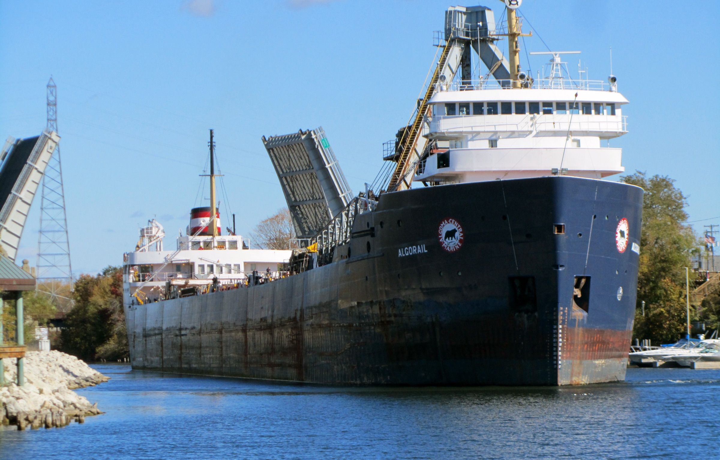 Great Lakes freighter Algorail moving up the Manistee River channel past raised drawbridges in downtown Manistee