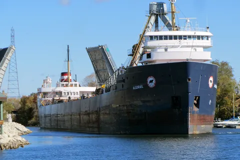Great Lakes freighter Algorail moving up the Manistee River channel past raised drawbridges in downtown Manistee