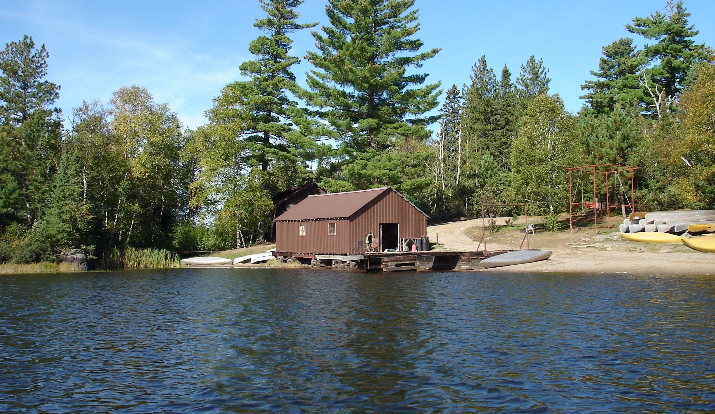 Boathouse, dock and beached canoes at Kawishiwi Lodge on Lake One, framed by tall pines