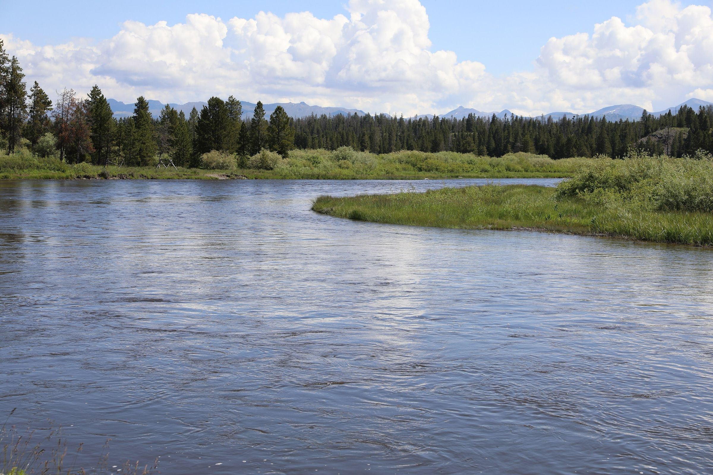 Clear water of the upper Madison River at Baker's Hole under summer clouds