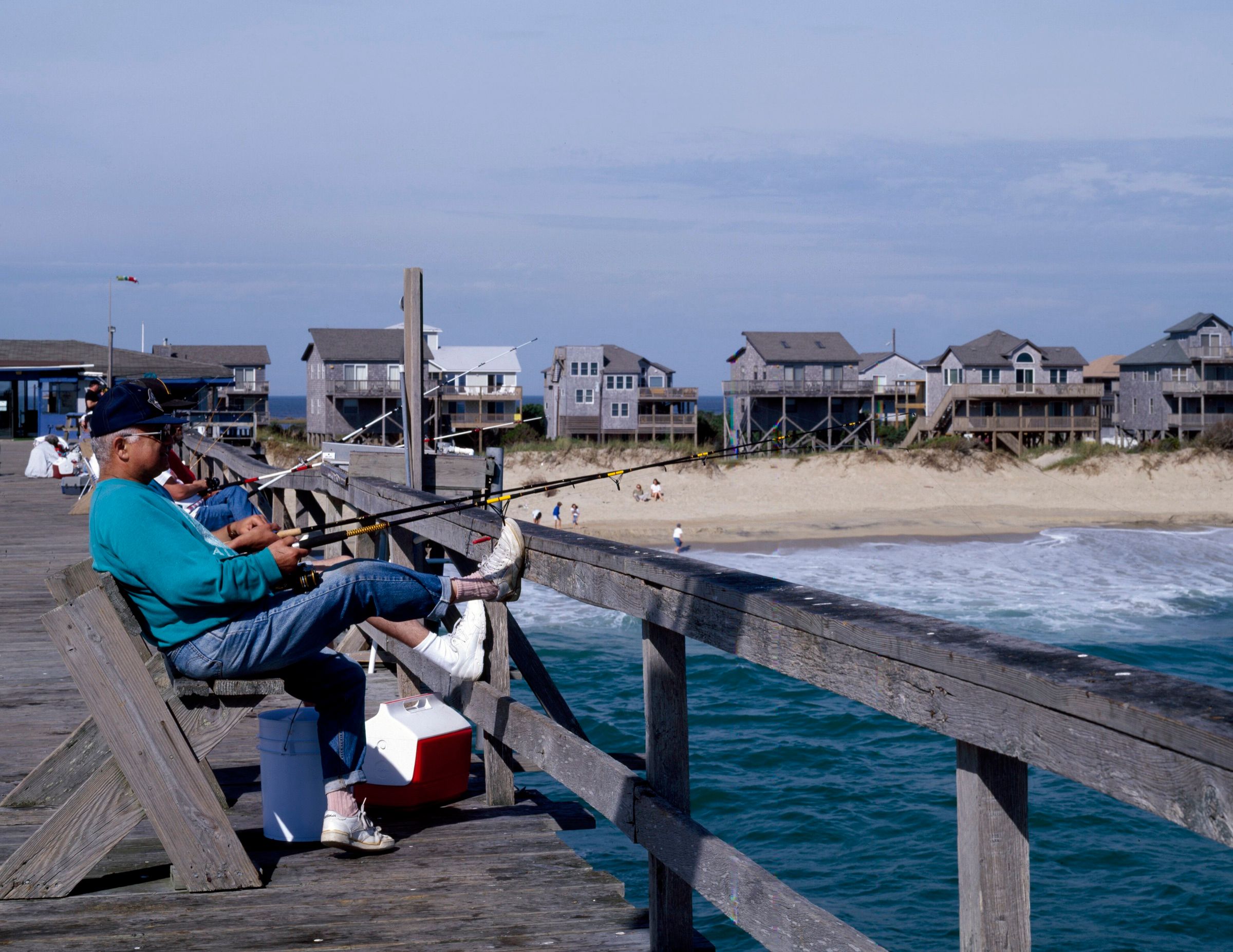 Angler surf fishing from the Hatteras fishing pier with beach houses behind