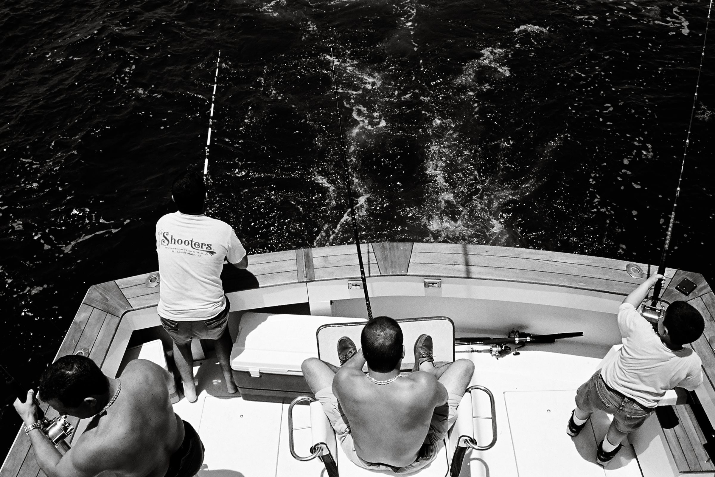 Black-and-white overhead view of anglers fishing from the cockpit of a sportfishing boat off Key West