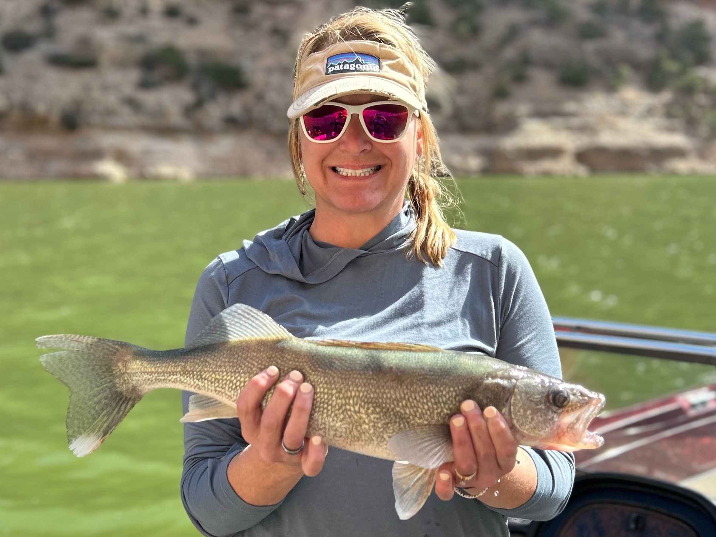 Smiling angler holding a walleye aboard a boat